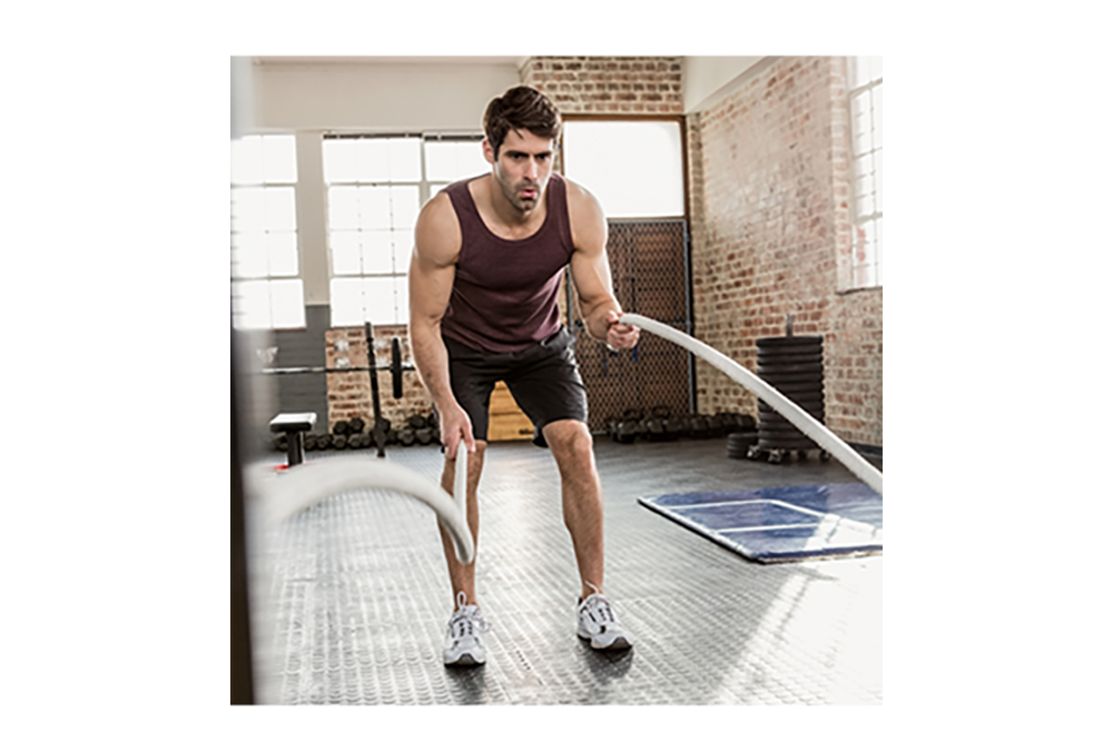 man in a gym using ropes for exercise